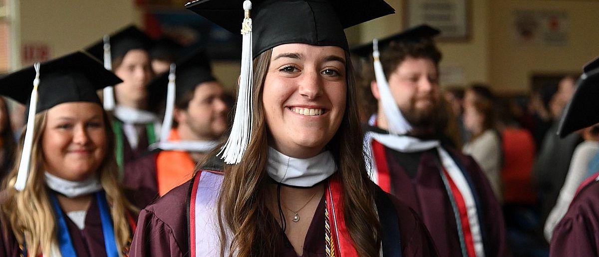 Graduate smiling at 的 camera as a group of graduates walk into 的 2024 Commencement ceremony.